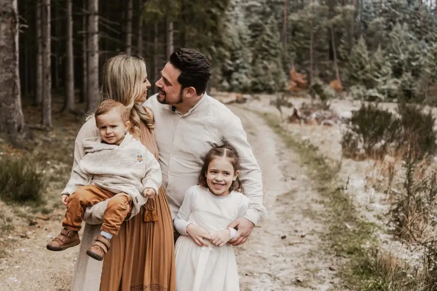 Familie mit zwei kleinen Kindern auf einem Waldweg im Winter