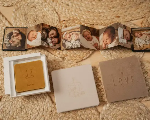 Ausgezogenes Leporello mit vielen Babyfotos, darunter drei Leinenboxen, eine davon mit der Prägung LOVE