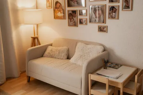 Gemütliche Studioecke mit hellem Sofa, Stehlampe und einer Wand voller gerahmter Familienfotos